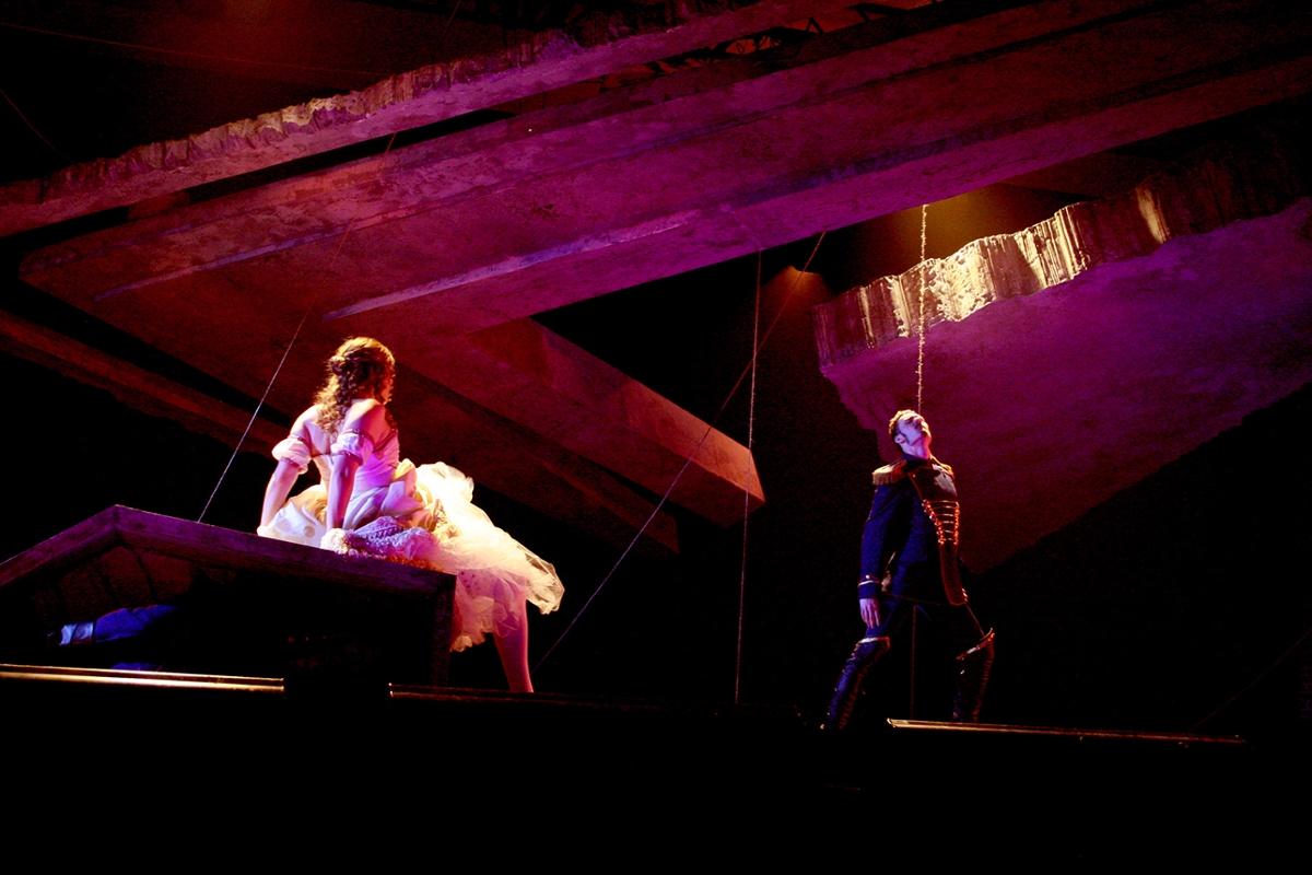 Feamale and male performers dramatically lit on stark stage